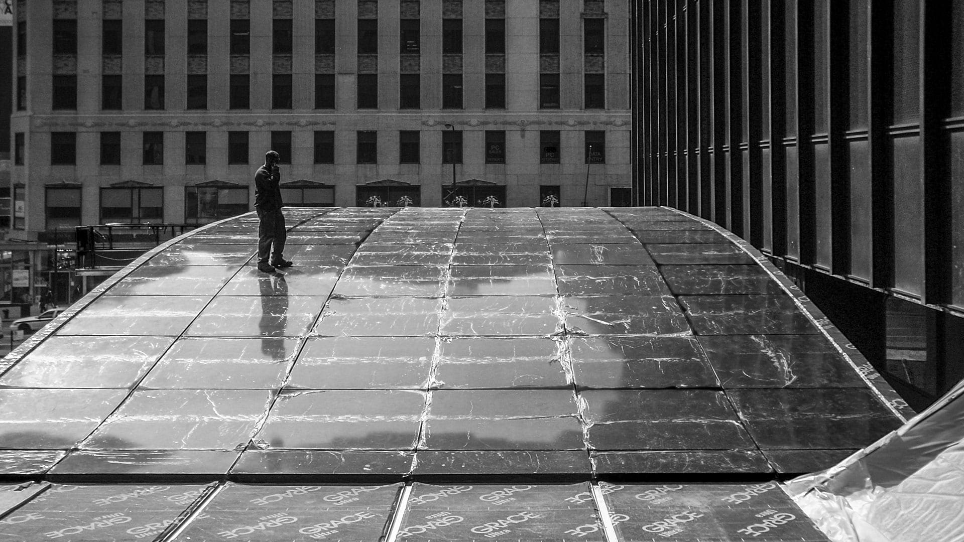 Construction photo shows a man standing on the top of the Michigan Avenue Plaza awning in Chicago.