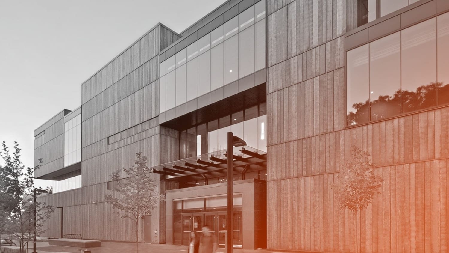 Students walking at dawn amidst the blue copper facade of the Instructional Centre.