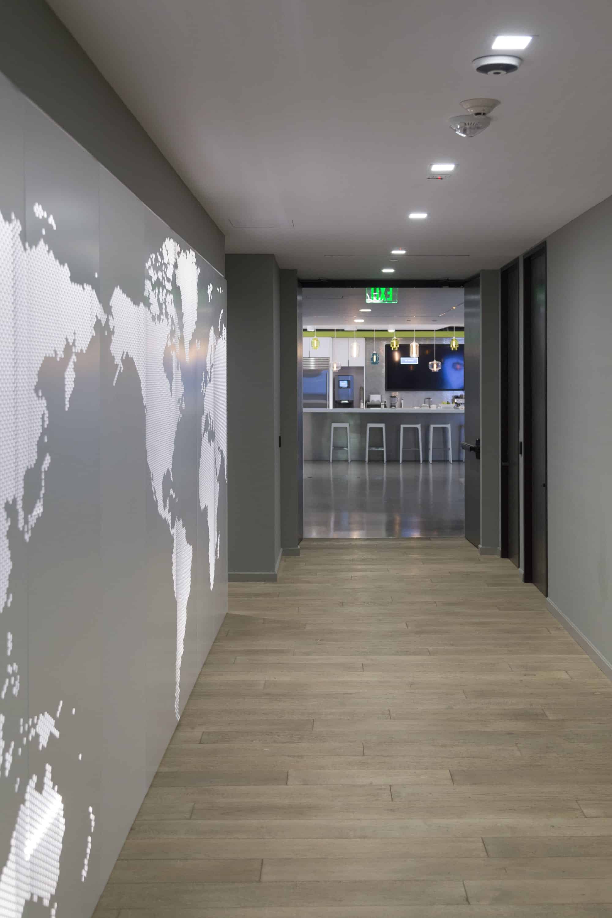 Backlit perforated metal serves as an accent wall between corporate spaces.