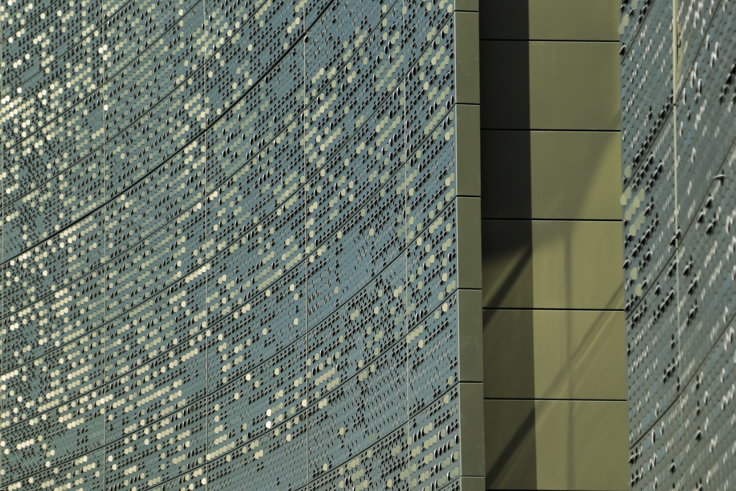 Detail of the louvered perforation patterns on color-shift iridescent painted aluminum panels.