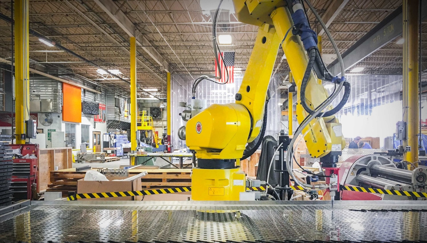 Zahner shop robotic arm places adhesive on perforated metal panels.
