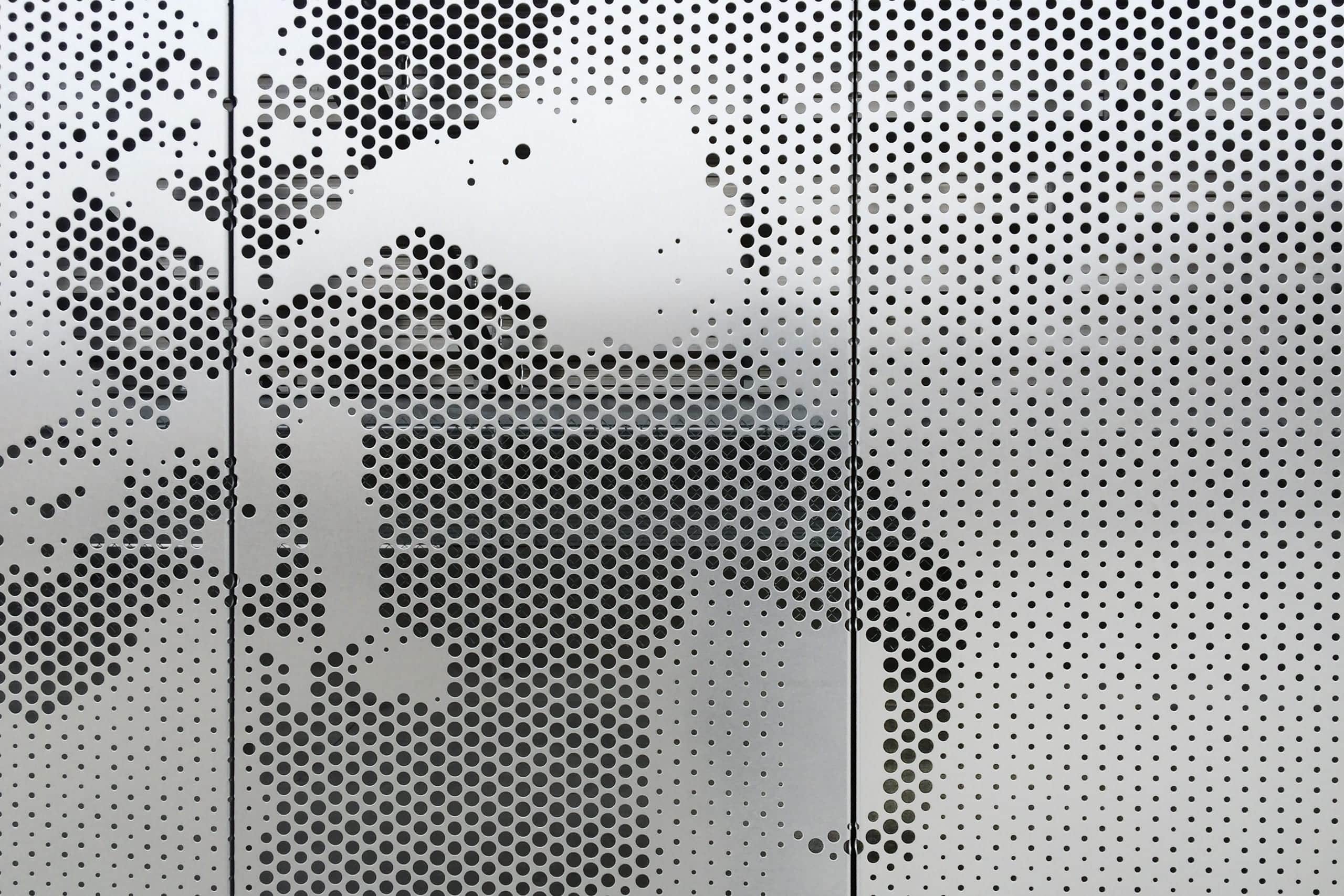 Detail of the Okie Blan<br /> chard Sports Complex perforated stainless steel.” /></picture>
<p class=