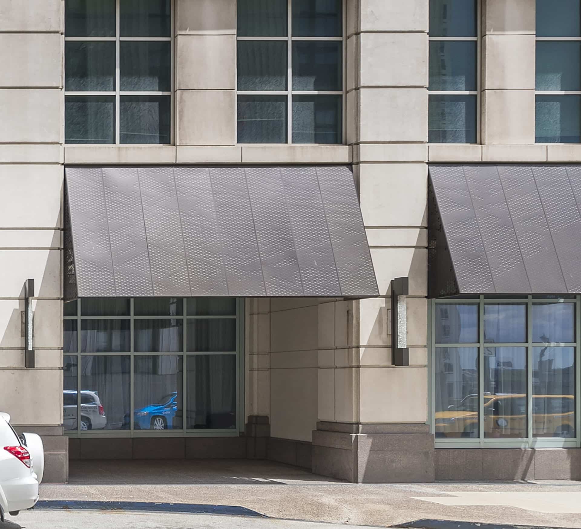 Anodized aluminum panels and structure for a series of awnings. Raised circles on the front create a pattern while still protecting from the elements.