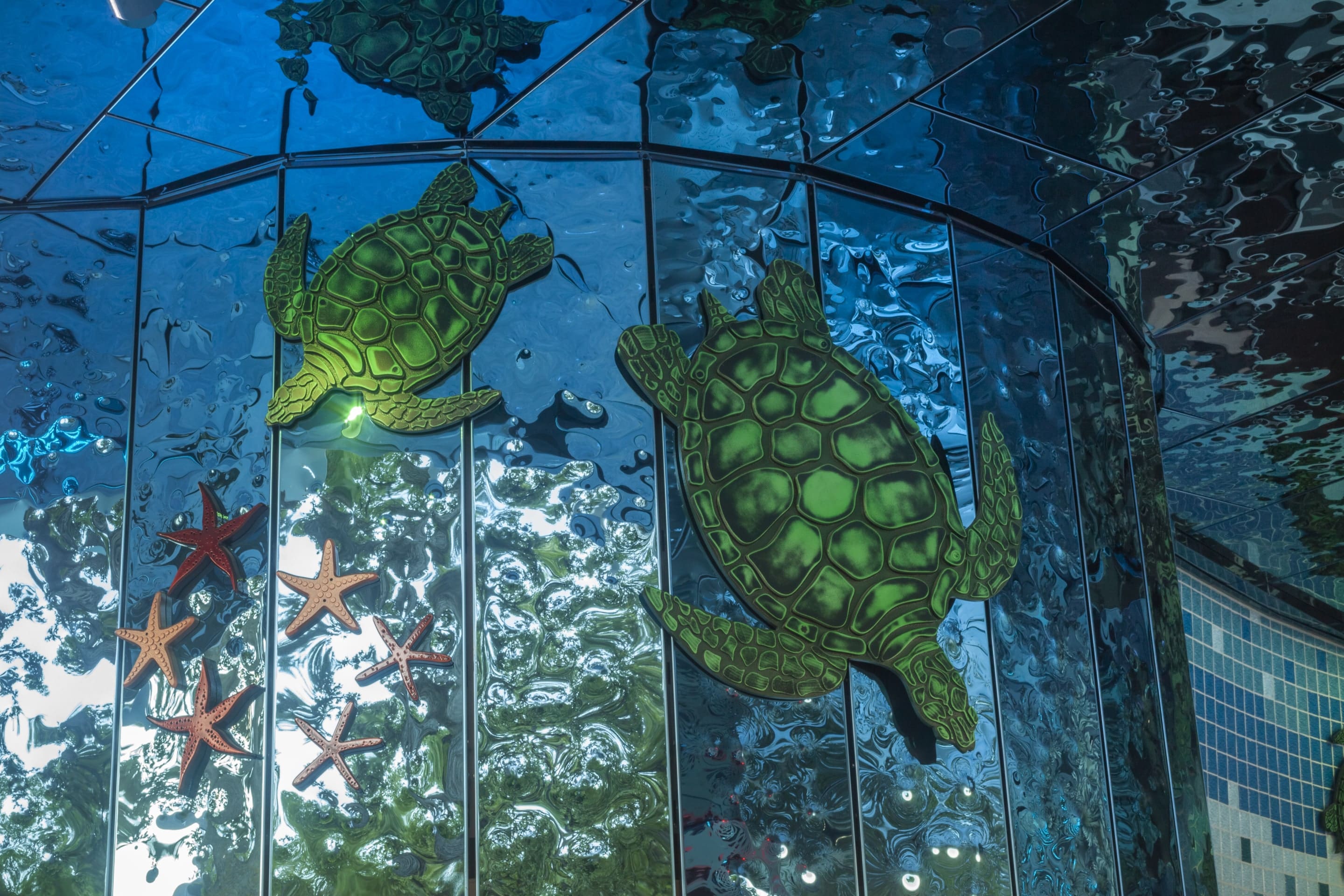Custom milled sea turtles and starfish against the rippled blue stainless steel cladding.