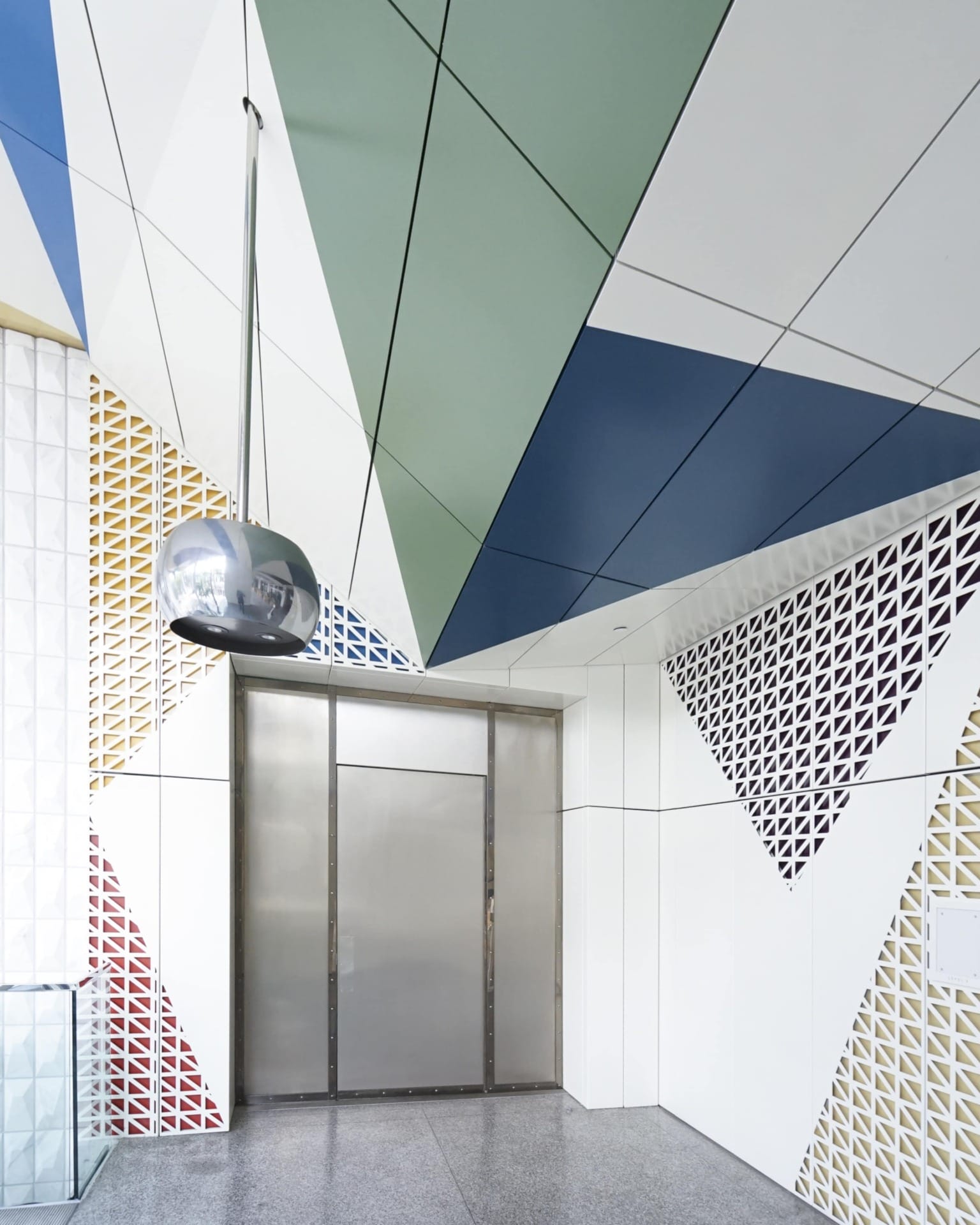 The triangular design motif that is rendered through painted aluminum on the soffit system continues into the wall system, which is rendered via perforated metal wall panels.