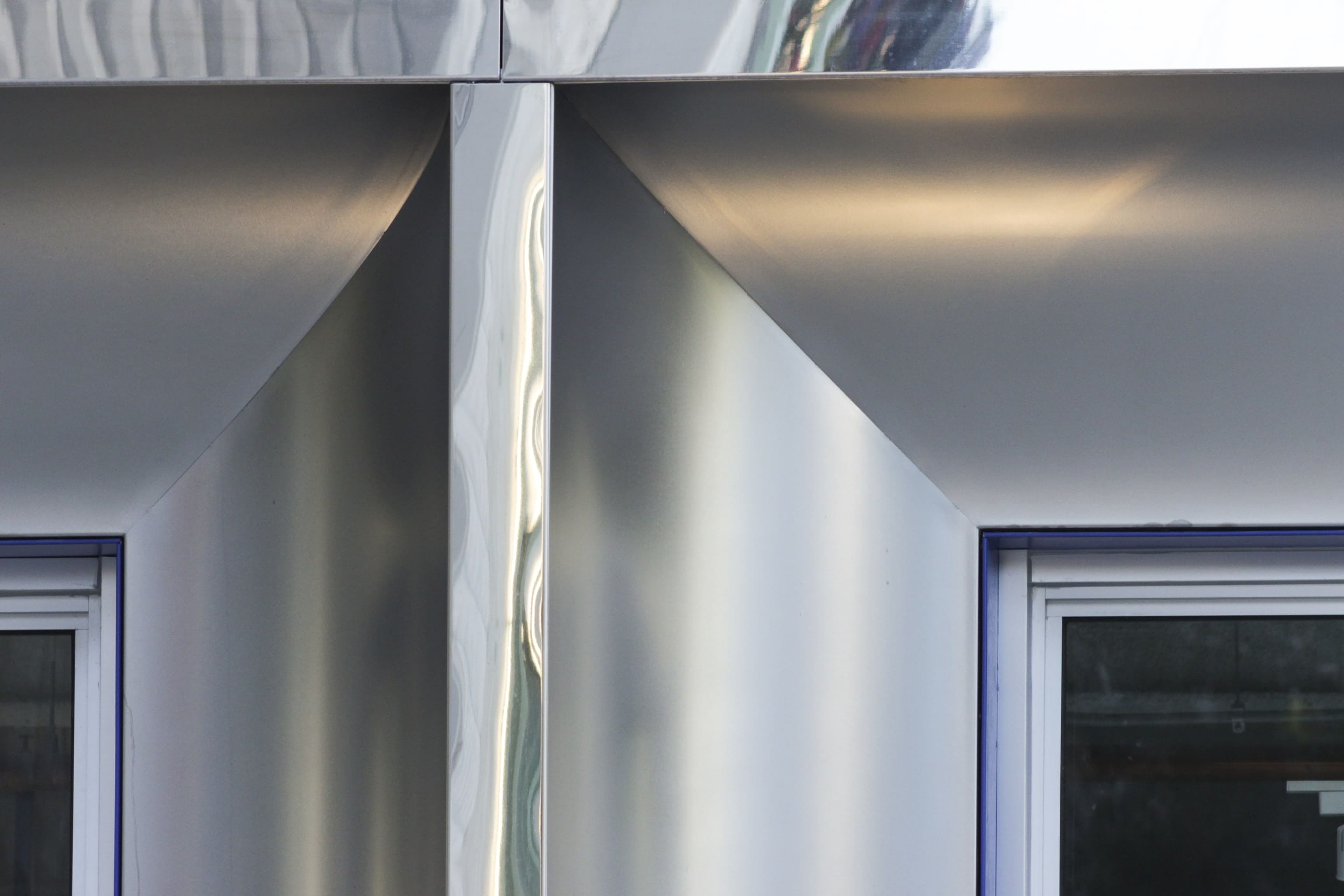Detail view of the mirror-polish stainless steel trim, Angel Hair cladding, and blue stainless window trim.