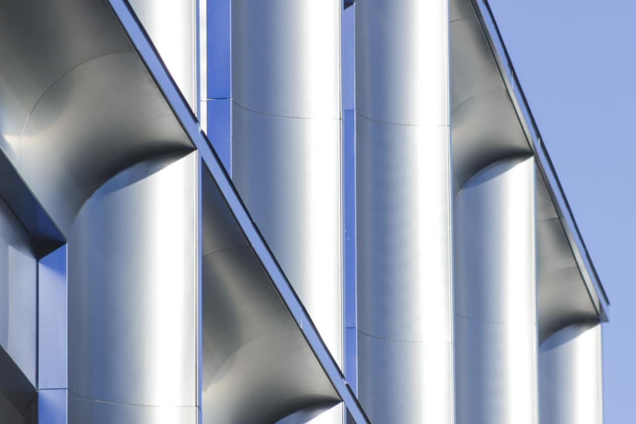The mirror-polish stainless steel trim reflects the sky, echoing the blue stainless steel of the window trim.