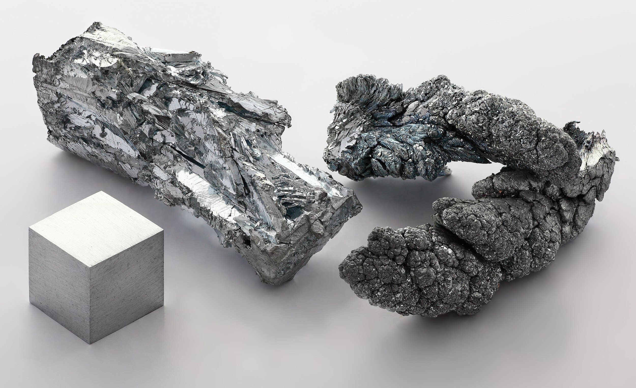 A 1 cubic centimeter, 99.995% pure zinc cube, a crystalline fragment of an ingot, and a sublimed dendrite.