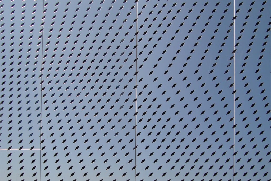 Diamond-shaped perforations in a metal panel system.